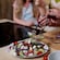 3 people standing at a counter with 2 hands holding forks above a plate of salad next to a cutting board with sliced onions